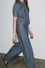 Pantalón de tiro alto con trabillas, bolsillos laterales y de parche en la espalda. Cierre frontal con cremallera y ganchos metálicos.