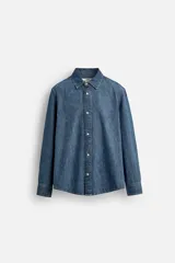 Camisa relaxed fit confeccionada en denim de algodón con cuello solapa, manga larga con puño abotonado, efecto lavado medio y cierre frontal con botones.