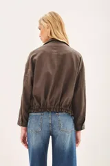 Campera marrón de lino con cierre frontal y bolsillos con solapa. Tiene mangas largas con presilla interna para arremangar.