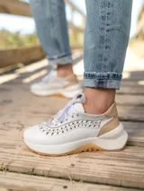 Zapatillas deportivas urbanas de cuero vacuno color blanco con detalles en cuero color beige y trenzado artesanal.