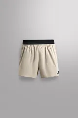 Shorts deportivos color beige con cintura elástica negra, bolsillos laterales y logo estampado en la pierna.