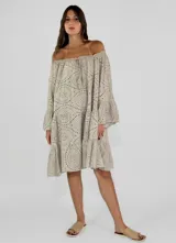 Vestido corto color beige con bordado calado, escote off-shoulder con lazo ajustable, mangas largas acampanadas y falda con volantes.