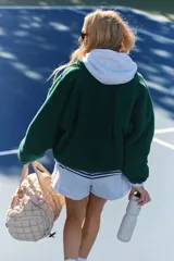 Chaqueta de polar suave y esponjosa color verde oscuro, con cierre a presión frontal, bolsillos con cremallera y parches de nailon. Tiene una silueta ligeramente oversize y llega justo por debajo de la cintura.