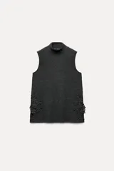 Top de punto canalé color gris oscuro, de cuello alto y sin mangas. Presenta apliques de encaje floral en los laterales del ruedo.