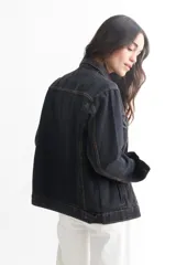Campera de jean azul con cuello clásico, cierre frontal con botones metálicos, bolsillos con solapa abotonada en el pecho y bolsillos laterales.