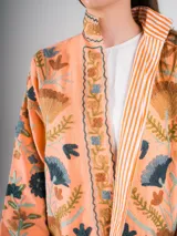 Chaqueta color salmón con bordado floral estilo Suzani en tonos azules, marrones y verdes.