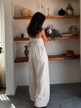 Mono largo color beige, con escote fruncido y tirantes finos con cuentas decorativas. El diseño es holgado y fluido.