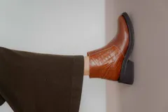 Bota corta color marrón con textura símil cuero de cocodrilo, caña baja, punta redondeada y taco cuadrado.