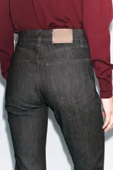 Jeans de tiro alto color negro, corte slim fit y bootcut, con cinco bolsillos y cierre frontal con cremallera y botón.