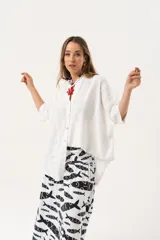 Camisa blanca con calados, escote en V, abotonada y manga 3/4.