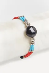 Pulsera elástica con tres hilos de cuentas de vidrio rojas y celestes, separadas por cuentas plateadas con diseño calado.