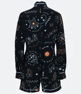 Enterito corto negro con estampado de aliens y texto en blanco y naranja. Tiene cuello camisero, cierre frontal con botones y mangas largas con puños arremangados. Incluye riñonera negra.