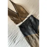 Pantalón de cuero negro y marrón con corte texano y flecos en el lateral.