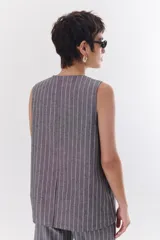 Chaleco gris con finas rayas verticales blancas, con cuello en V, cierre frontal con botones y bolsillos laterales.