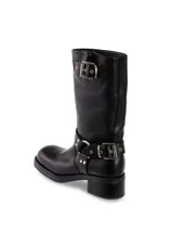 Bota de cuero negra de media caña con hebillas plateadas en el tobillo y en la parte superior de la caña.