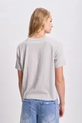 Remera gris claro de corte recto con cuello redondo y mangas cortas. Estampa frontal con la frase "Always Rockin'" en strass.