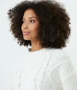 Suéter blanco de punto trenzado con cuello redondo y mangas largas.
