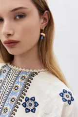 Aros de argolla dorada con dije colgante en forma de hongo de resina roja y blanca con incrustaciones de strass.