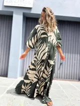 Vestido largo camisero de manga larga, con cuello mao y botones frontales. Presenta un estampado grande de hojas en color verde oscuro y crudo, con corte en capas en la falda.