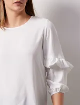 Blusa de gasa blanca, marca Sioni, con mangas 3/4 y aplique de volados.