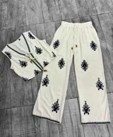 Conjunto de pantalón y chaleco blancos con bordados rojos. El chaleco es corto, con escote en V y se ata en el frente. El pantalón es recto y de tiro alto.