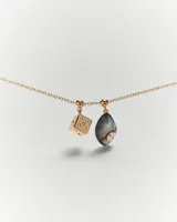 Aro colgante dorado con forma de dado y detalles de circonitas blancas.