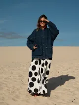 Campera de jean azul oscuro, de corte oversize, con cuello clásico, cierre frontal con botones metálicos, bolsillos con solapa en el pecho y estampado de lunares grandes en blanco y negro en la espalda.