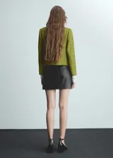 Chaqueta corta de tweed verde con botones joya, cuello redondo, cuatro bolsillos delanteros y mangas largas.