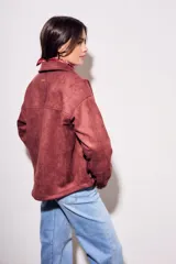 Sobrecamisa color borgoña de gamuza sintética con cuello camisero, cierre frontal con botones a tono, bolsillos de parche con solapa en el pecho y mangas largas con puños abotonados.