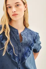 Camisa celeste de algodón con apliques de encaje a tono en pechera y mangas. Cierra con botones de pasta a tono en el frente. Puños con elásticos que generan efecto balloon.