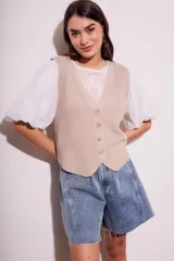 Chaleco de punto color beige con cuello en V y cierre frontal con botones.
