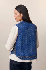 Chaleco acolchado azul con estampado floral, cuello redondo y cierre frontal con botones de madera.