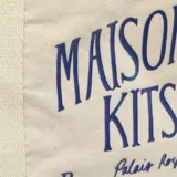 Bolso tote de algodón color crudo con asas de cinta y estampado azul con el logo de la marca Maison Kitsuné y la leyenda "Paris, France".