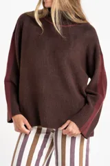 Sweater negro de tejido grueso con cuello alto acanalado. Presenta una franja decorativa en las mangas y el cuello en hilo marrón con brillo (lurex).