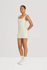 Vestido corto blanco de tenis con recortes de entalle y falda evasé. Posee un short interno con bolsillo.