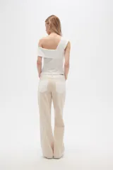 Pantalón jean color beige, de corte recto y holgado, con cintura alta y diseño color block en la parte superior.