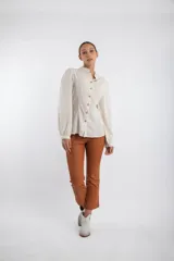 Camisa color crudo con cuello mao, abotonada al frente con botones de madera, mangas largas abullonadas y corte entallado.
