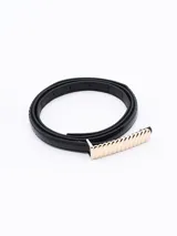 Cinto negro de cuero sintético con hebilla rectangular dorada con diseño acanalado.