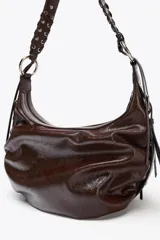 Bolso de hombro marrón oscuro con efecto craquelado, asa con detalles de flecos y anillas metálicas. Incluye bolsillo interior con cierre de cremallera.