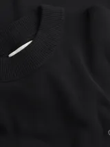 Sweater negro de punto de algodón suave con cuello alto y corte relaxed. Presenta el logo de Calvin Klein bordado en el pecho.