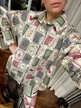 Camisa de lino con estampado de cartas de juego y dados, de corte clásico, con cuello camisero, cierre frontal con botones de madera y mangas largas.