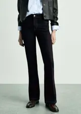 Pantalón de jean de tiro medio, color azul oscuro, con diseño acampanado y cinco bolsillos.