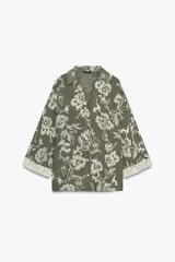 Camisa verde militar con bordado floral blanco, cuello solapa, escote en pico, manga tres cuartos con detalle de guipur y cierre frontal con botones.