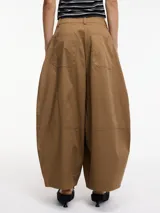 Pantalón slouchy color marrón con bolsillos laterales y traseros, pretina con botón y cierre.