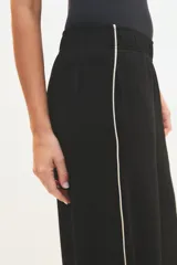 Pantalón palazzo negro con cintura elástica y una fina línea blanca vertical en los laterales.