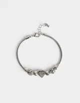 Pulsera plateada flexible con dijes de metal y strass, incluyendo un dije de corazón.