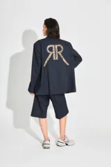 Saco sastrero oversize confeccionado en sarga color azul marino, con estampado de doble R con diseño animal print en la espalda. Tiene botones frontales, bolsillos delanteros y está forrado con tafeta a tono.
