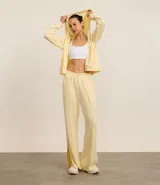 Pantalón deportivo recto color amarillo pastel, de media malla, con cintura elástica, bolsillos laterales y abertura en el ruedo.