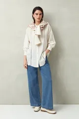 Camisa blanca de lino con botones de nácar, corte recto, cuello clásico y mangas largas con puños abotonados. Presenta detalles de calados tipo vainillas en el frente y las mangas.