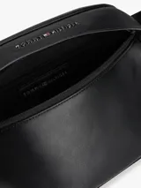 Riñonera negra de poliuretano con logo metálico de Tommy Hilfiger en el frente, correa ajustable con cierre de apertura fácil y panel de malla acolchado en la parte trasera.